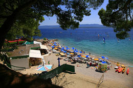 Pláž a půjčovna windsurfingů a kajaků v letovisku Bol, ostrov Brač, Chorvatsko
