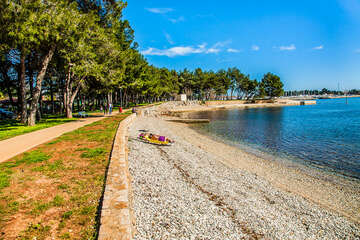 Novigrad - oblázková pláž s promenádou, Istrie, Chorvatsko