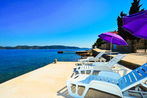Prázdninový dům Riva - betonové molo s lehátky a slunečníky před domem, Mali Iž, ostrov Iž, Chorvatsko